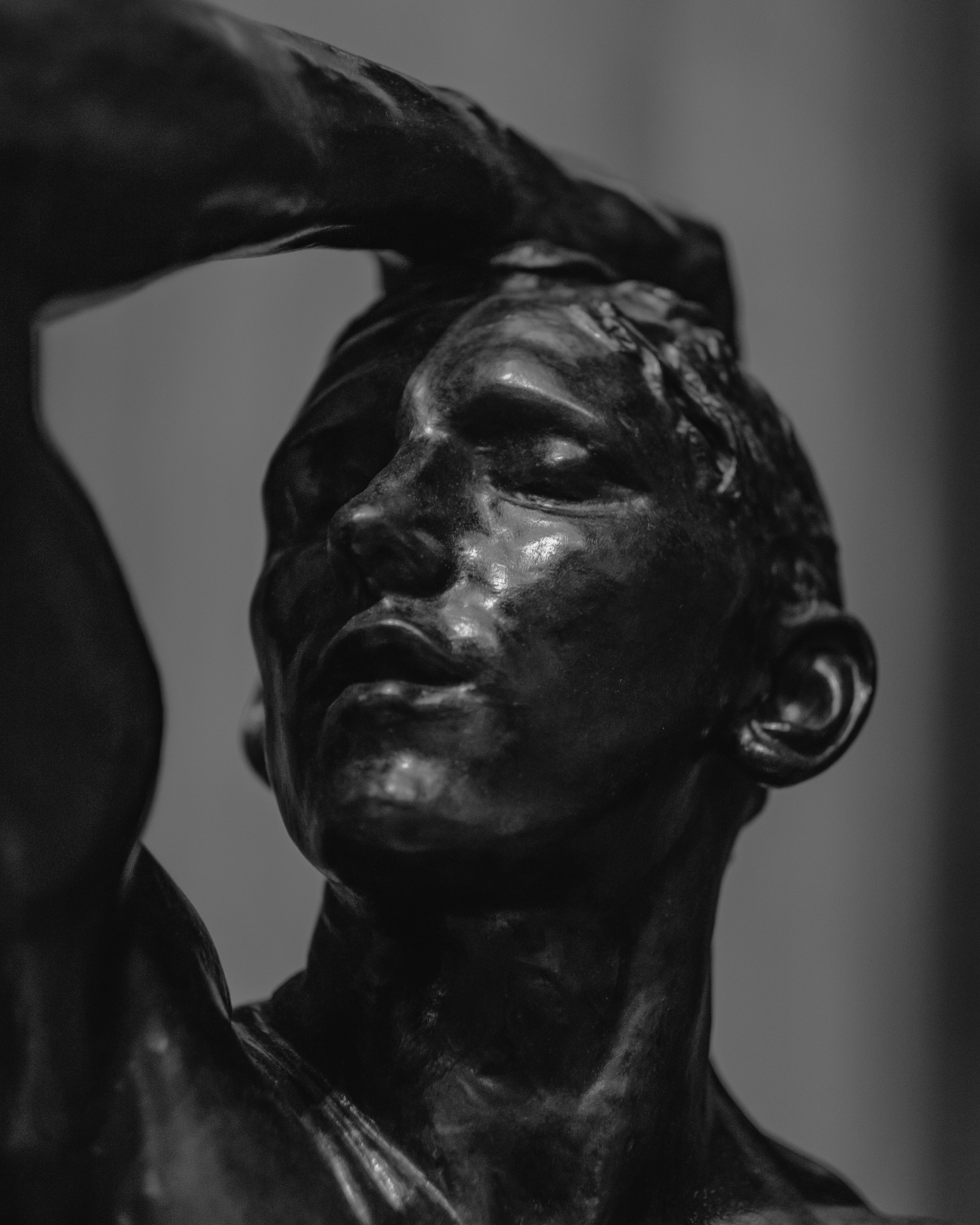 Bronze statue in all black, hand on head in dramatic pose